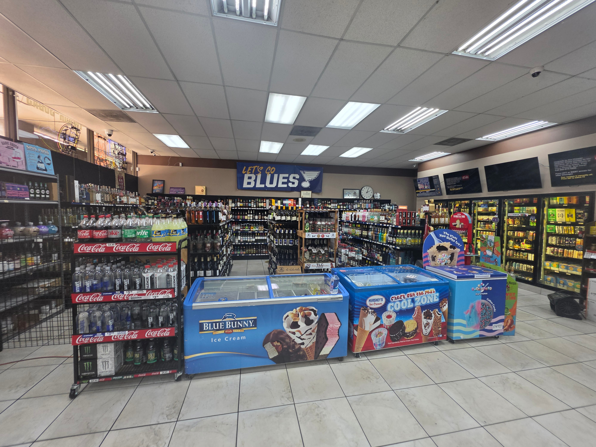 The interior of James Henry Provisions Co., with bottles on shelves, beverage coolers and freezers.